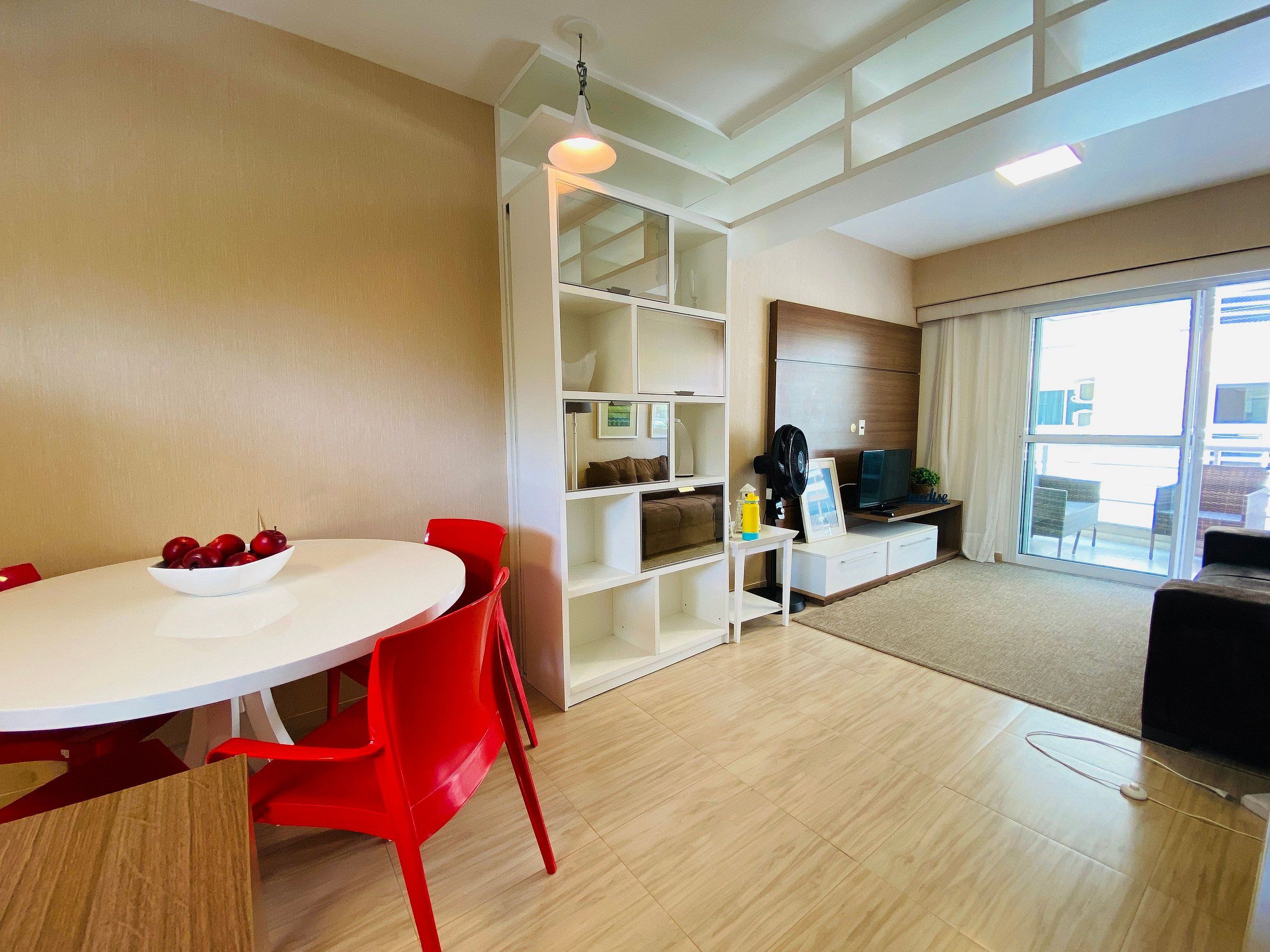 A modern living room with a dining area, a TV, and a large window.