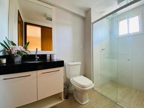 Un baño moderno con inodoro, lavamanos y ducha.