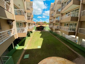 Une cour intérieure avec un petit bâtiment, entourée d’immeubles résidentiels à plusieurs étages dotés de balcons.