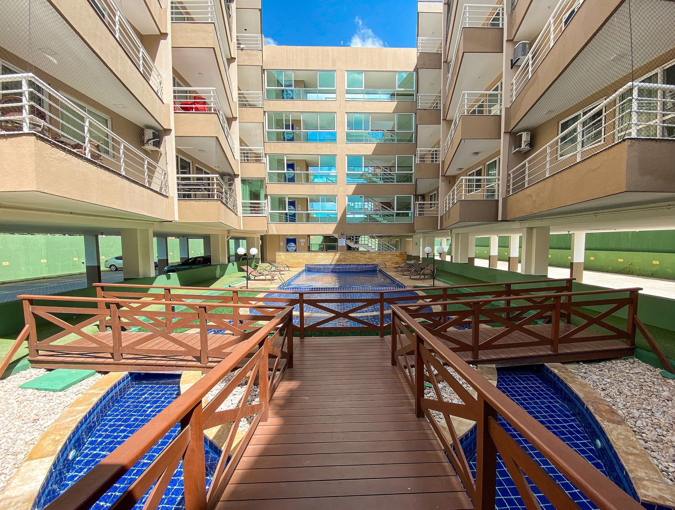 Un hotel de varios niveles con una piscina central, zona de estar exterior y un paseo cubierto.