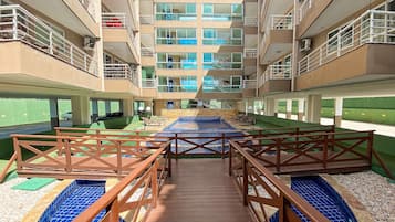 Un hotel de varios niveles con una piscina central, zona de estar exterior y un paseo cubierto.