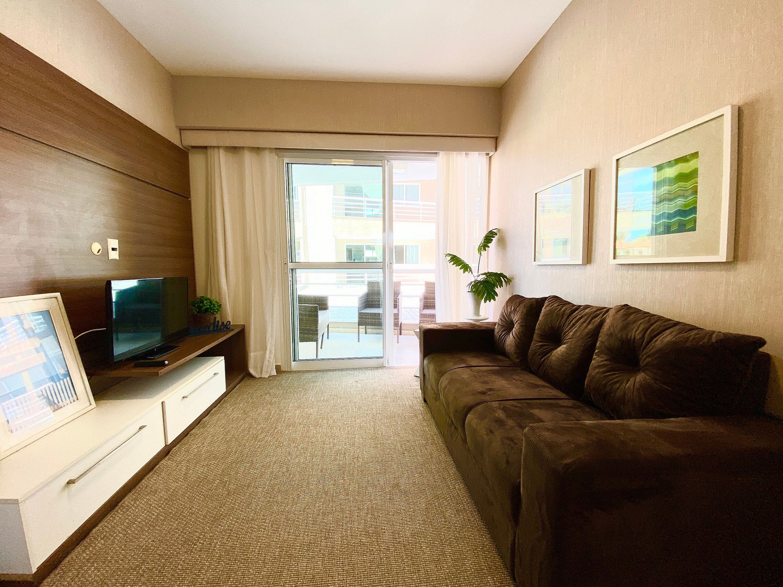 A living room with a sofa, television, and a sliding glass door leading to an outdoor area.
