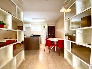Una cocina moderna con armarios blancos, una isla central y sillas rojas.