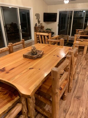 A wooden dining table with chairs, a television mounted on the wall, and a sliding glass door. - The Graceful Retreat: Secluded Cabin w/ Hot Tub (Sevierville)