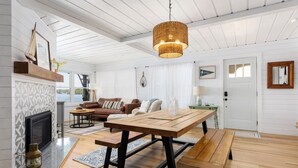 A spacious living room with a fireplace, a dining table, and a large window overlooking a body of water.