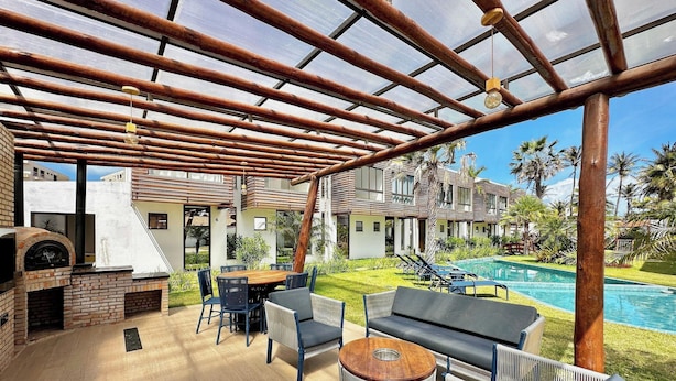 A covered outdoor area with a pool, lounge chairs, and a barbecue grill. - Bella Arte Porto das Dunas (Aquiraz)