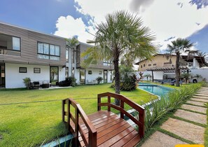 Un bâtiment moderne doté d’une piscine, d’une terrasse en bois et d’une pelouse bien entretenue.