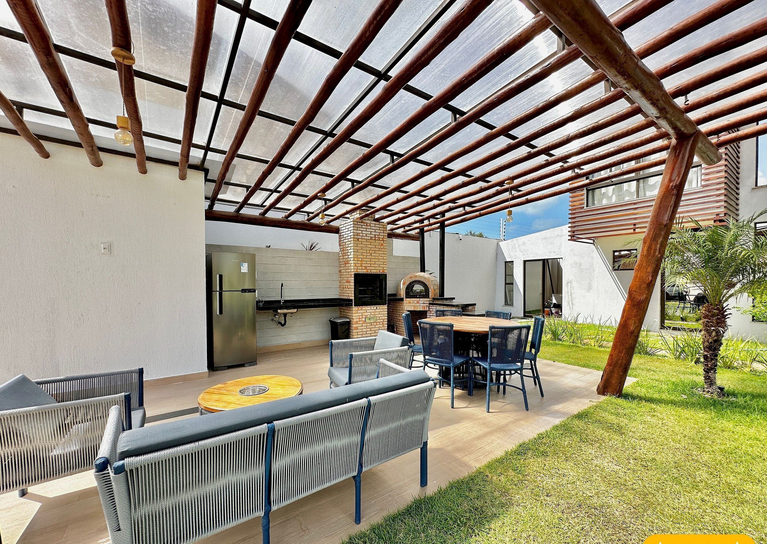 Une terrasse extérieure équipée d’un barbecue, de sièges et d’une structure en forme de pergola.