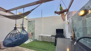 Un patio con una hamaca, una jaula colgante, una parrilla y una mesa.