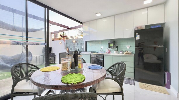 Una cocina moderna con comedor, ventanas amplias y un refrigerador.