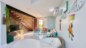 Un interior moderno con una escalera de piedra, un televisor de pantalla plana, muebles de mimbre y decoración mural.