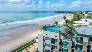 A hotel with a rooftop pool, a beach view, and a modern architectural design. - Vila Porto Beira Mar - VSH (Ipojuca)