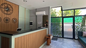 A reception desk with a wooden panel design, a modern air conditioning unit, and a glass door leading outside. - Rodis Hotel (Menderes)