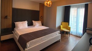 A hotel room with a bed, a chair, a desk, and a window with curtains. - Rodis Hotel (Menderes)
