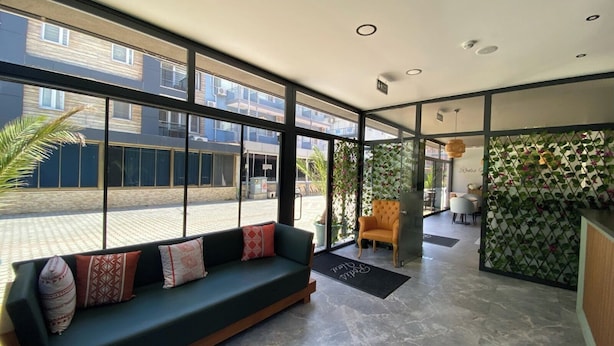 A modern lobby with a sofa, a chair, and a reception desk. - Rodis Hotel (Menderes)