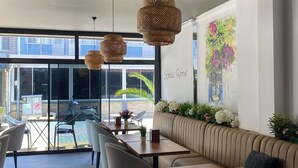 A modern interior with a seating area, tables, and hanging lights. - Rodis Hotel (Menderes)