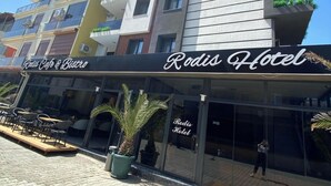 A modern building with a sign for 'Rodis Hotel' and a cafe named 'Rodis Cafe & Bistro' on the ground floor. - Rodis Hotel (Menderes)