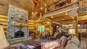 L’intérieur d’une cabane en rondins, avec une cheminée en pierre, des meubles en cuir et un plafond en bois rustique.