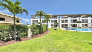 Un hotel con piscina, palmeras y un césped bien cuidado.