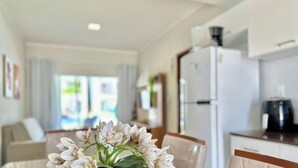 Una cocina moderna con refrigerador, cafetera y un comedor con mesa y sillas.