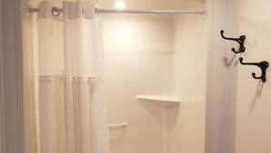 Una doccia con tenda, una vasca da bagno bianca e uno scaffale.