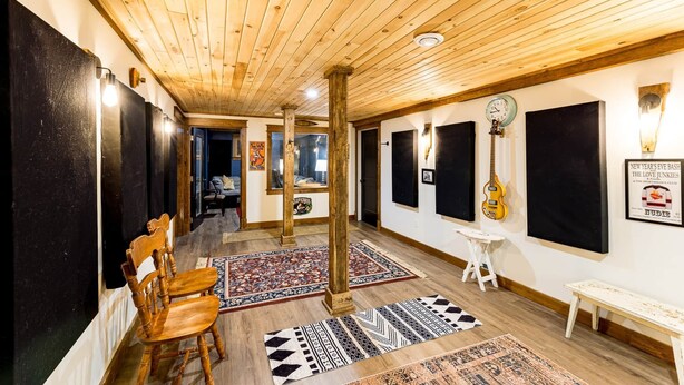 Ein Flur mit Holzboden, schwarzen schallabsorbierenden Paneelen, einem Holzstuhl, einem kleinen Hocker und einer Bank.