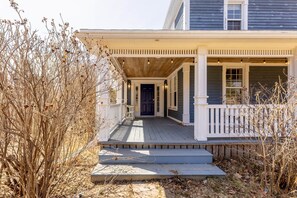 A two-story house with a porch, a front door, and a small staircase leading to the entrance. - The Porch Light - 5 Bedroom Retreat with music room. (Hope River)