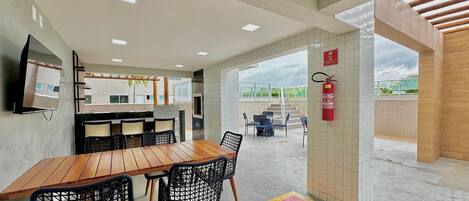 A modern interior with a wooden table and chairs, a TV mounted on the wall, and a view of an outdoor patio area.