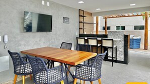 Un espace intérieur moderne avec une table et des chaises en bois, un téléviseur à écran plat et une cuisine intégrée.