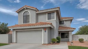A two-story house with a garage, a small front yard, and a clear sky. - Quiet Lakefront Home with Boat, Hot Tub, Game Room, Great Views, Sleeps 10 (Gilbert)
