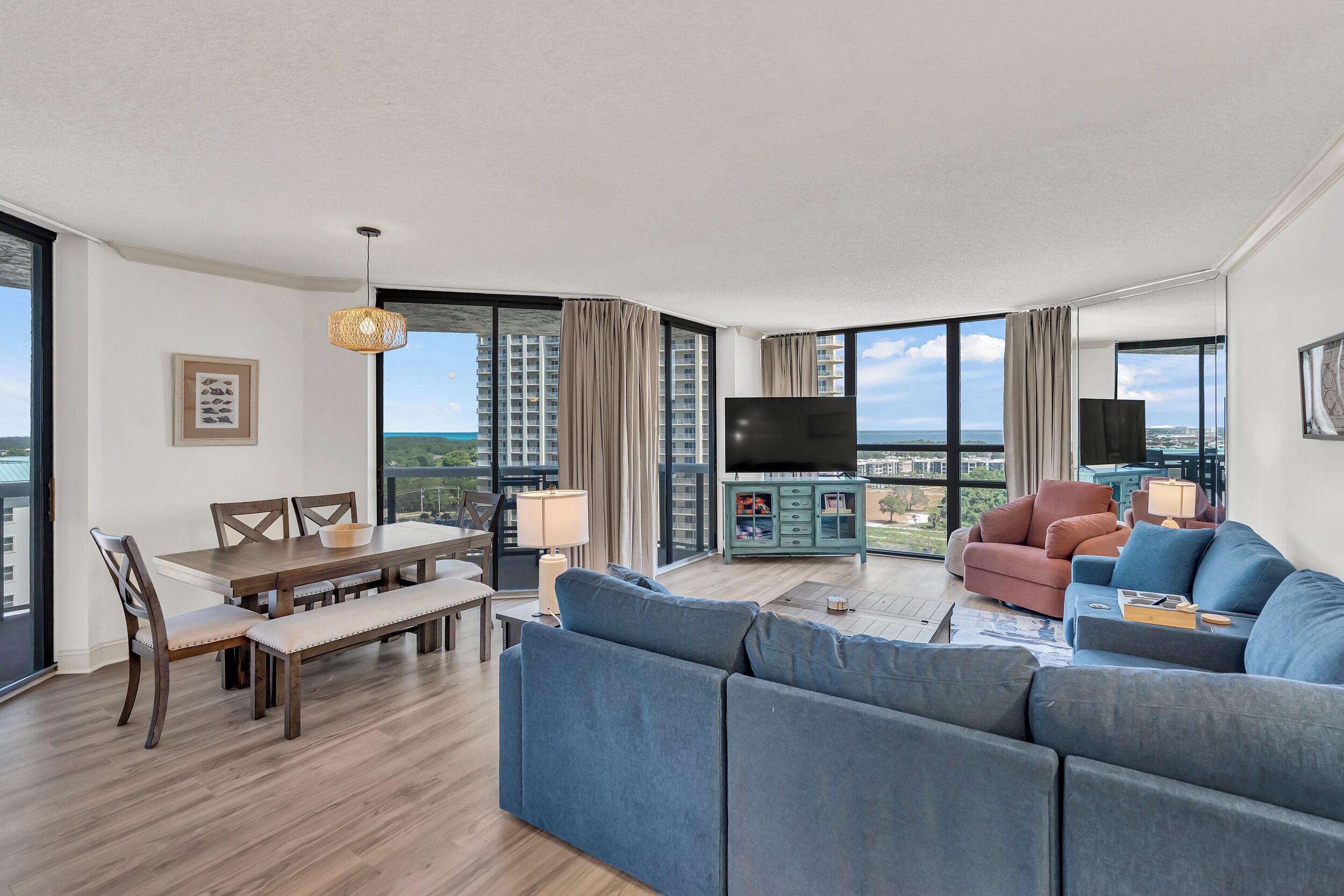 A modern living room with a large sofa, a dining table, and a TV.
