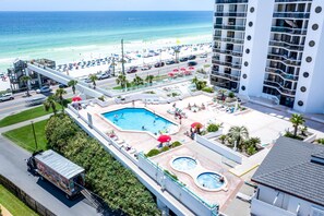 A hotel with a pool, beach view, and a multi-story building.