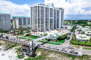 A multi-story hotel with a rooftop pool, a pedestrian bridge, and a beachside location.