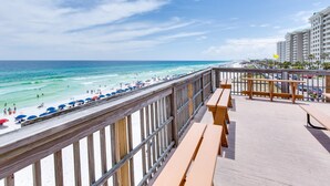 Blick auf den Strand von einem Balkon mit Holellentrail und Bänken.