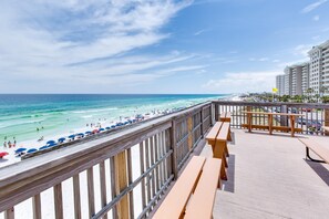 A beach view from a balcony with wooden railings and benches.
