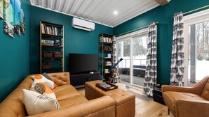 Ein Wohnzimmer mit türkisfarbenen Wänden, einem braunen Ledersofa, einem Fernseher und einem Bücherregal.