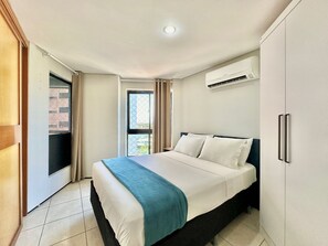 A hotel room with a bed, an air conditioning unit, a window with curtains, and a door leading to an outdoor area. - Apart-hotel Iate Plaza, Vista Completa da Orla de Fortaleza (Fortaleza)