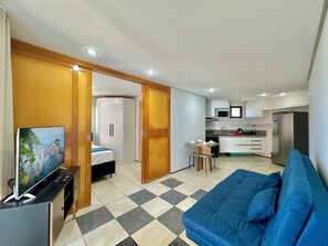 A compact living space with a kitchenette, a bed, a TV, and a blue sofa. - Apart-hotel Iate Plaza, Vista Completa da Orla de Fortaleza (Fortaleza)