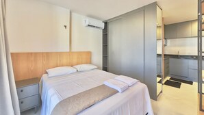 Une chambre d’hôtel moderne équipée d’un lit, d’une table de chevet, d’une armoire et d’une kitchenette.