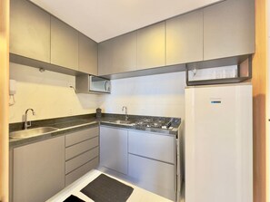 A compact kitchen with a built-in microwave, gas stove, and a refrigerator.