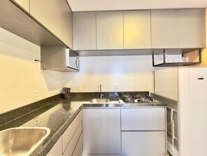 A compact kitchen with a gas stove, a sink, and a refrigerator.