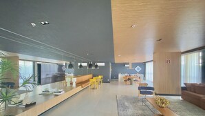 A modern hotel lobby with a long reception desk, seating area, and dining space. - Jsmart Dom (Fortaleza)