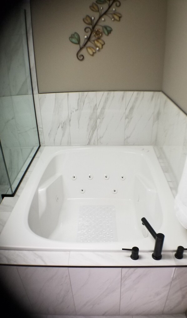 Un baño con bañera blanca, cabina de ducha de vidrio y un adorno de pared.