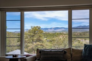 A room with a large window offering a view of a mountainous landscape. - Near Santa Fe Plaza, Luxury Outdoor Space, Hot Tub (Santa Fe)