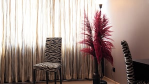 Ein Zimmer mit einem zebra-gestreiften Sessel, einer hohen, roten Pflanze und einem zebra-gemusterten Sofa.