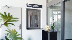 Ein Empfangsbereich mit Schild, Tür, Fenster, Blumentopf und Glaswand.