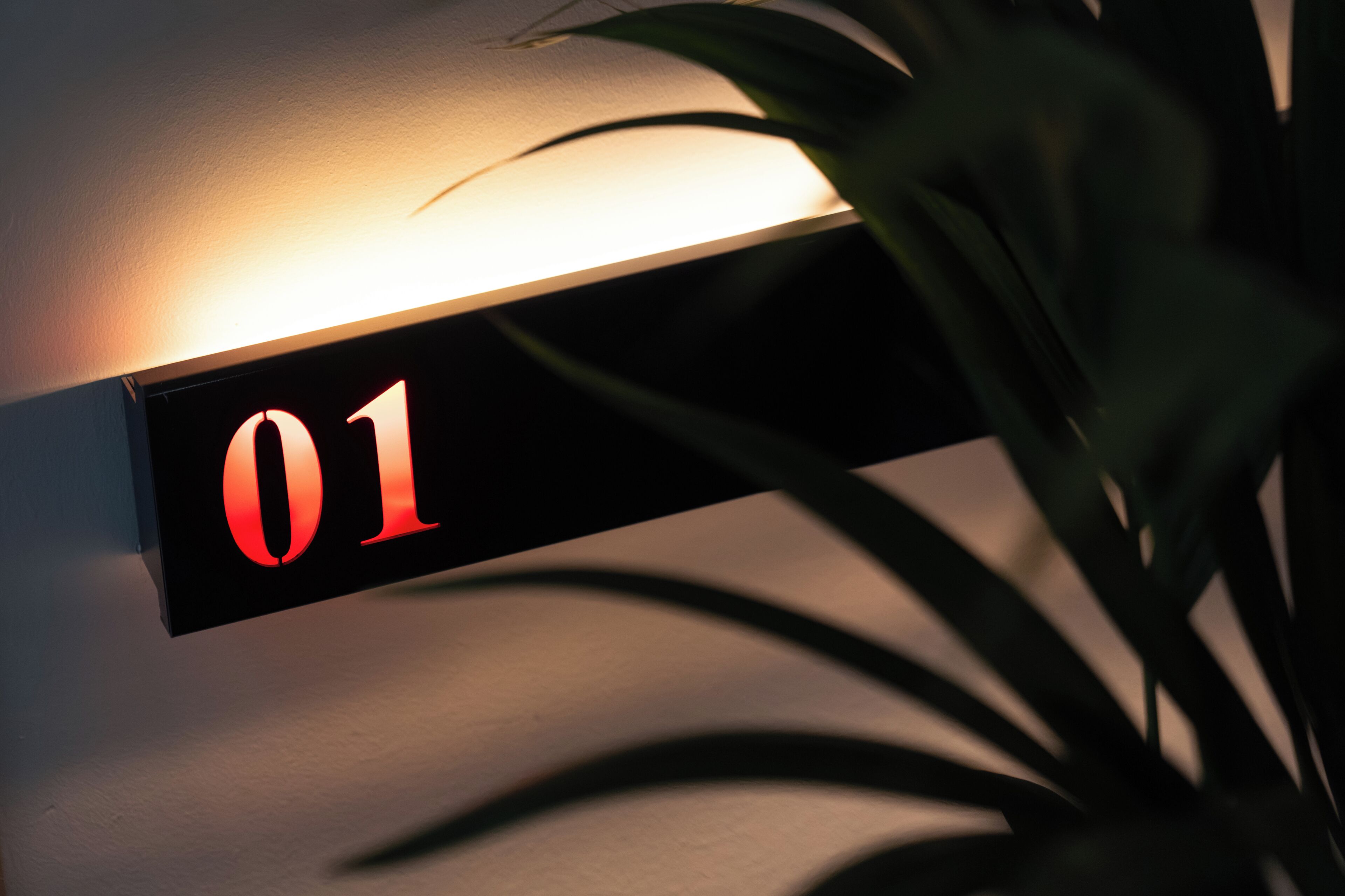 A wall-mounted sign with the number '01' illuminated in red.