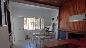 Un salon avec un canapé rouge, une table à manger avec des chaises, un téléviseur et une cheminée.