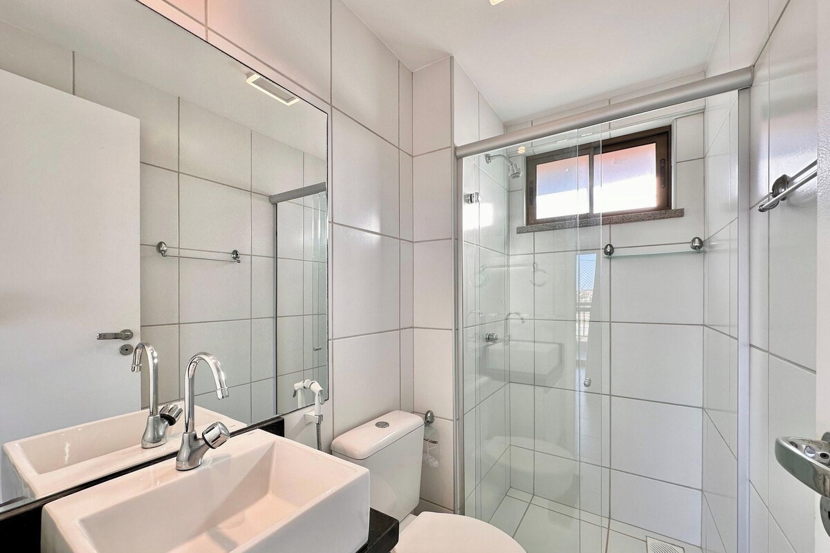A modern bathroom with a glass-enclosed shower, a white sink, and a toilet.