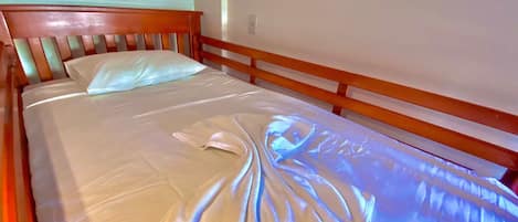Un lit avec un drap blanc et une couverture pliée.